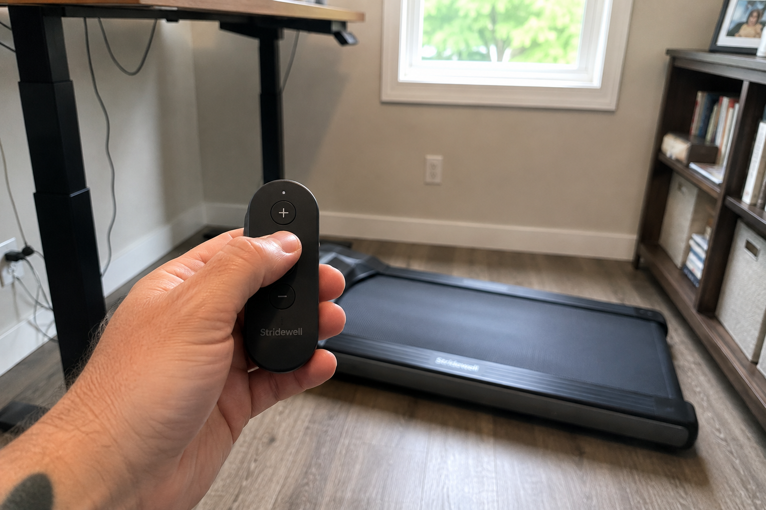 Hand holding a walking pad remote with the pad in the background